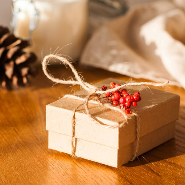 Craft Christmas gift box on a wooden table surrounded by cones and dried oranges. A gift with your own hands. Copy space High quality photo