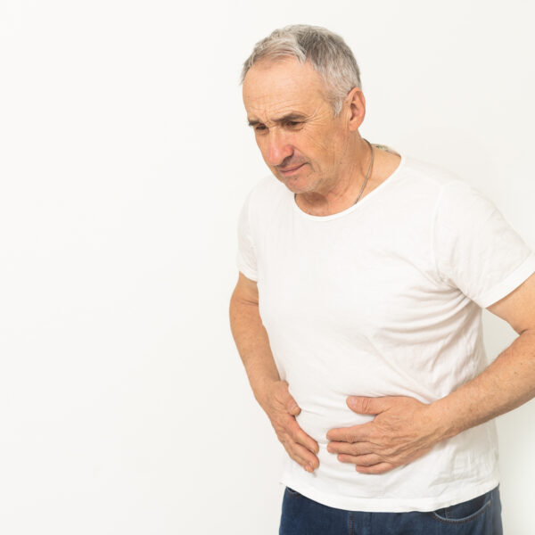Elderly men have abdominal pain sitting on the sofa in the house. Concept Problems of the digestive tract in older people, health care