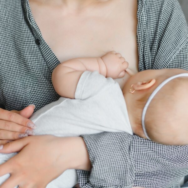 Lactation concept. Young mother breastfeeding her newborn baby at home, close up